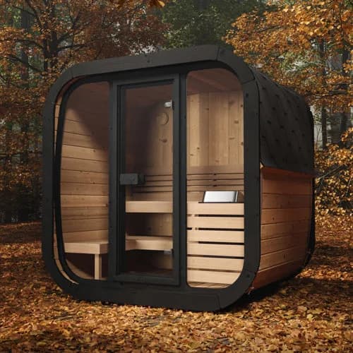 SaunaLife's rendering of the CL5G cube sauna, a full glass front and a dark shingled roof, standing on autumn leaves among trees.