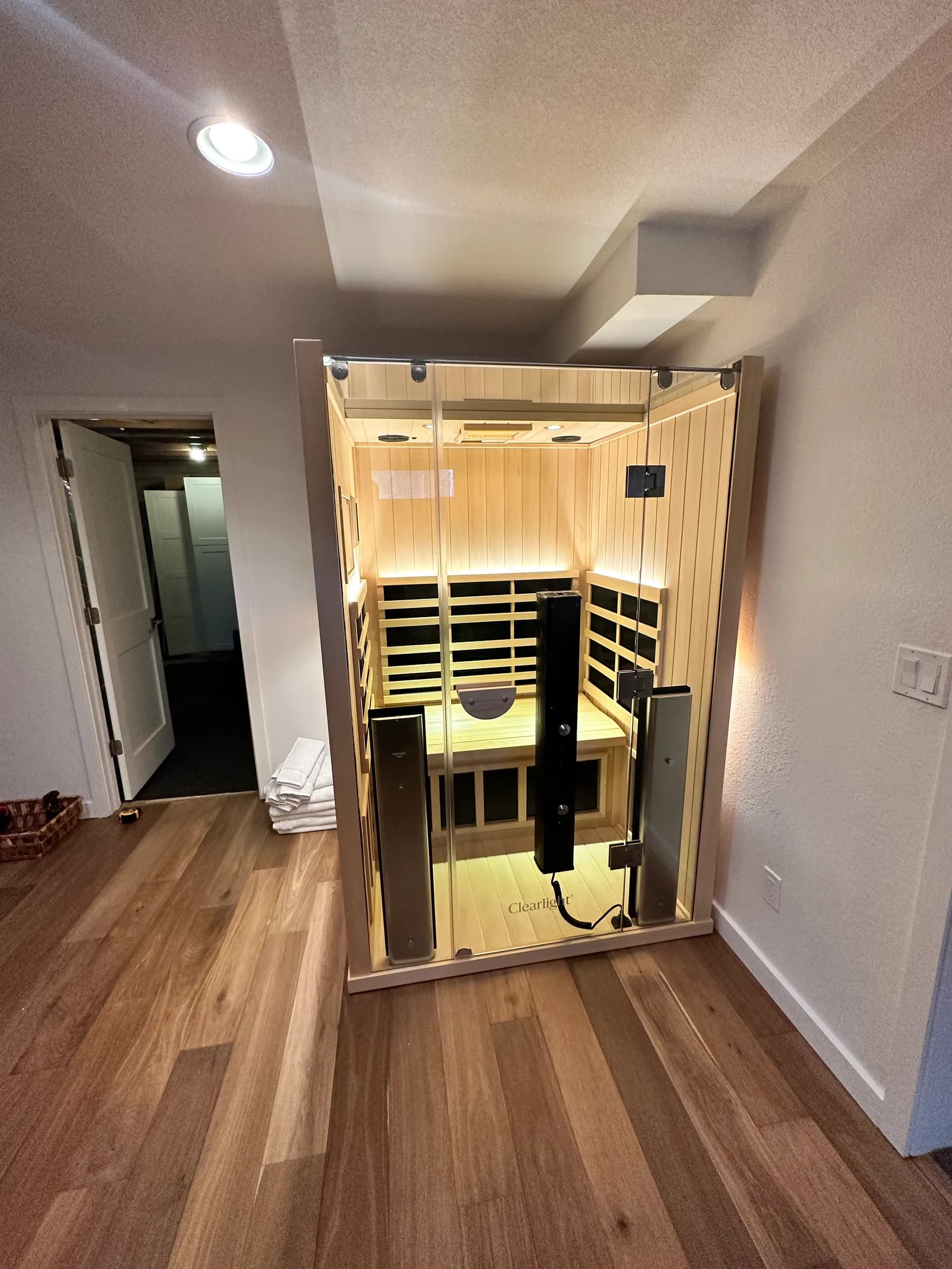 A Clearlight infrared cabin we installed at the end of a finished hallway on a wood floor in Colorado, lit from inside.
